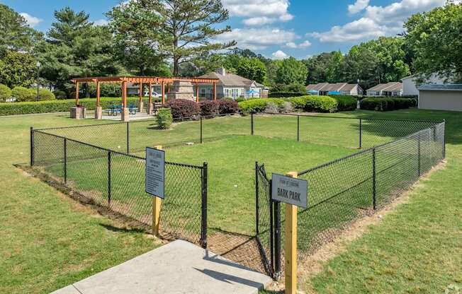 a fenced in park with a playground and a picnic area