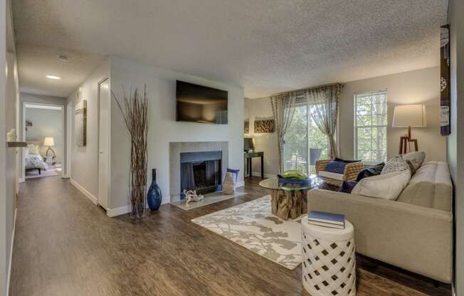 Apartments for Rent in Beaverton - Cedar Crest - Spacious Living Room with Large Windows, Fireplace, and Wood-Style Flooring Leading to the Bedroom