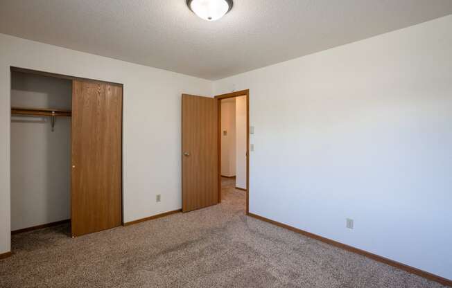 a bedroom with carpet and a door to a closet. Fargo, ND Southview Village Apartments