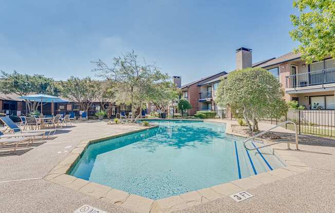 A pool surrounded by a fence and chairs.