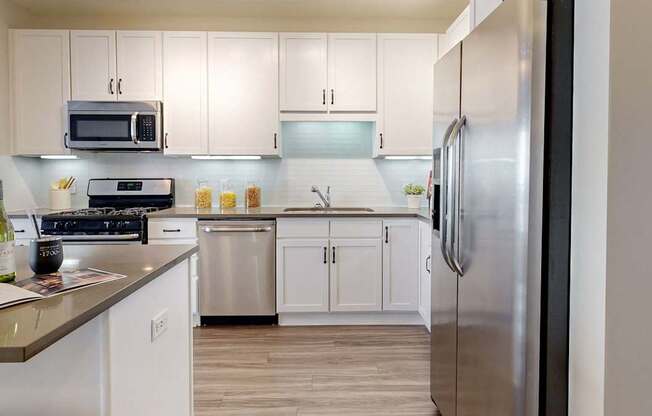 A modern kitchen with white cabinets and stainless steel appliances.