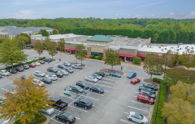 an aerial view of a parking lot filled with cars and a shopping center