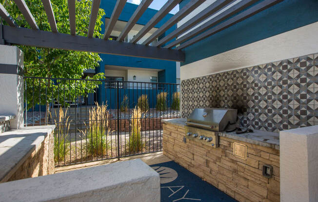 an outdoor kitchen with a grill and a blue house