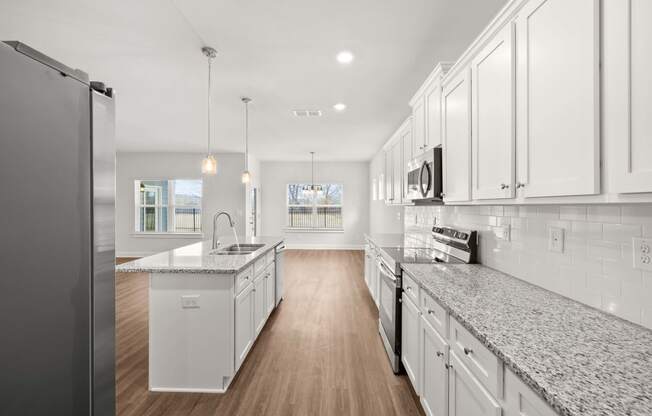 a large kitchen with marble counter tops and white cabinets