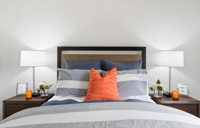 a bedroom with a bed with blue and orange pillows