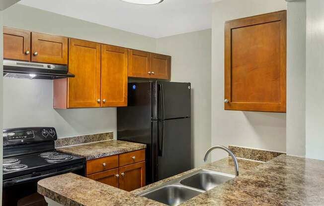 A kitchen with granite countertops and a black refrigerator.