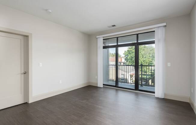 Hibernia living room with rich vinyl plank flooring and large sliding glass doors with custom window coverings leading out to a private balcony