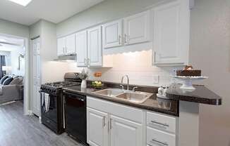 A kitchen with black appliances and white cabinets.