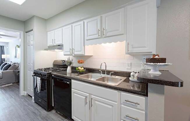A kitchen with black appliances and white cabinets.