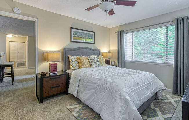 A bedroom with a bed, nightstand, and a ceiling fan.
