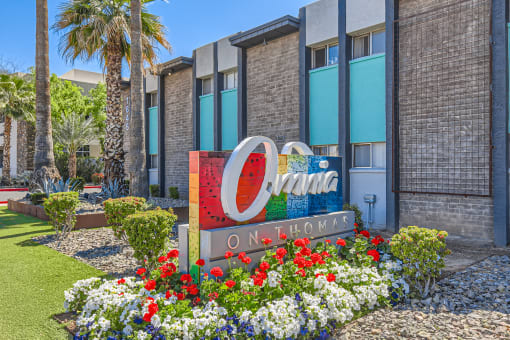 an apartment building with ao omni olympia sign in front of flowers