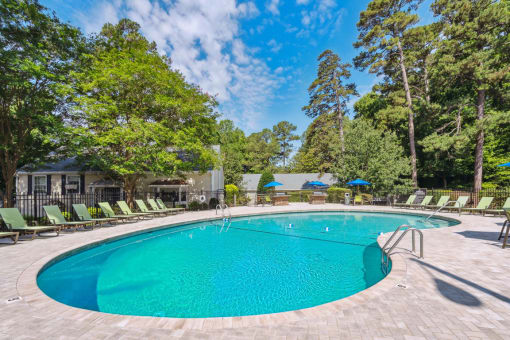 a swimming pool with lounge chairs and trees in the background  at Lake Johnson Mews, Raleigh, 27606