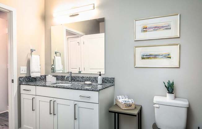 A bathroom with a toilet, sink, and two framed pictures on the wall.
