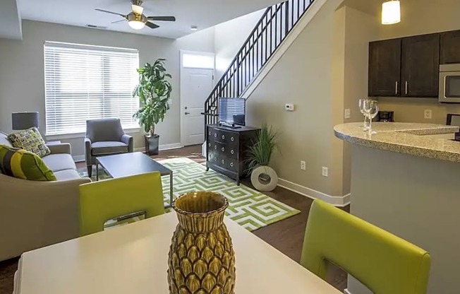 A living room with a white table and green chairs.
