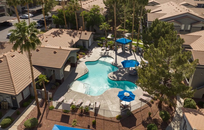 an aerial view of a resort style swimming pool with umbrellas