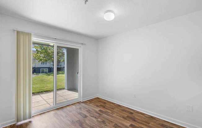 a living room with white walls and a sliding glass door to a yard