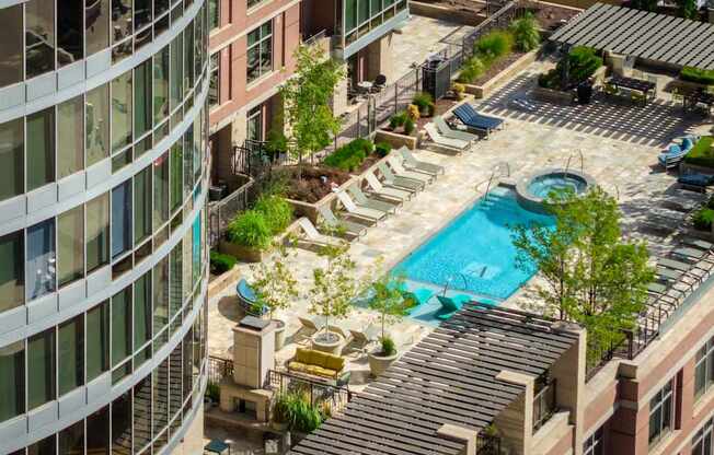 A rooftop pool area with lounge chairs and a hot tub.