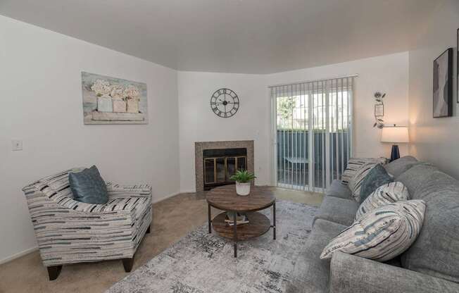 A living room with a grey couch, a wooden coffee table, and a painting on the wall at Sierra Glen Apartments, California, 95621