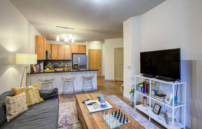 A modern living room with a grey couch, a wooden coffee table, and a flat screen TV on a white stand.