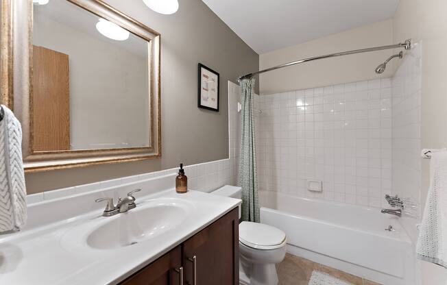A white sink with a gold faucet and a toilet in a bathroom.