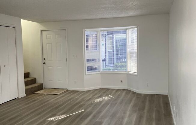 an empty living room with a window and wooden floors