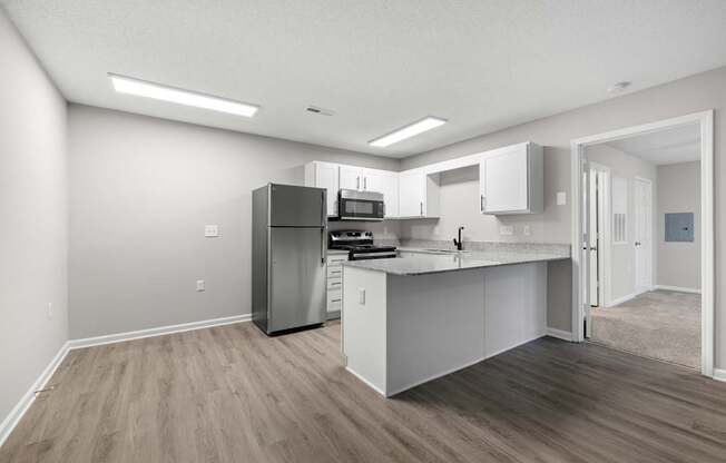 A kitchen with white cabinets and a wooden floor.