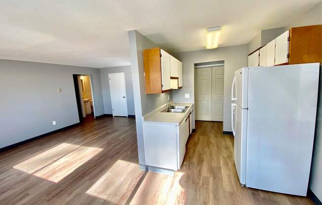 A kitchen with white appliances and wooden floors.