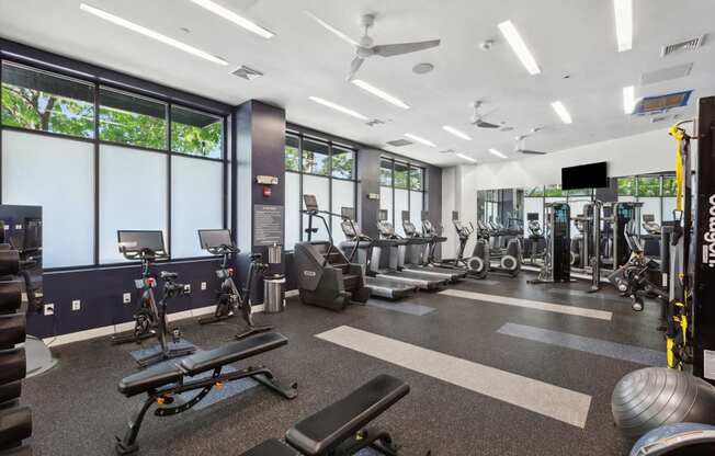 A gym with a variety of equipment including treadmills, weights, and exercise machines.