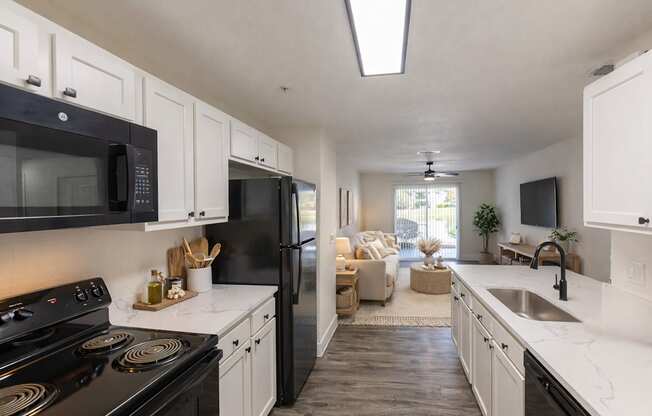A modern kitchen with black appliances and white cabinets.