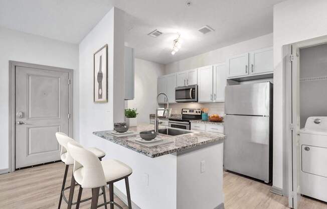 A kitchen with a white countertop and white chairs.