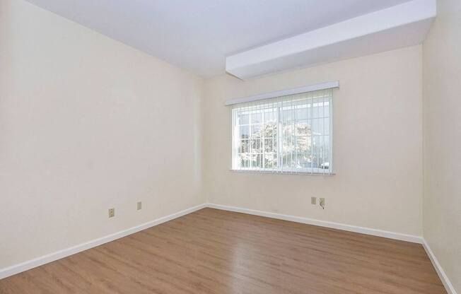 Empty room with a window and wooden floor.