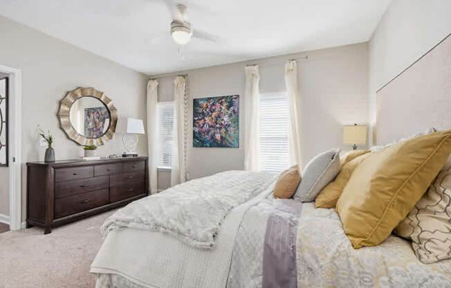 A bedroom with a large bed and a dresser with a mirror.