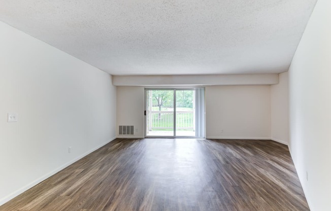 an empty living room with a sliding glass door leading to a patio