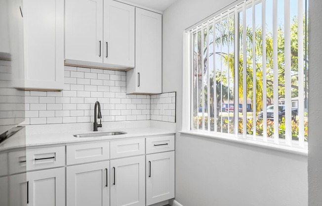 A kitchen with white cabinets and a white sink.
