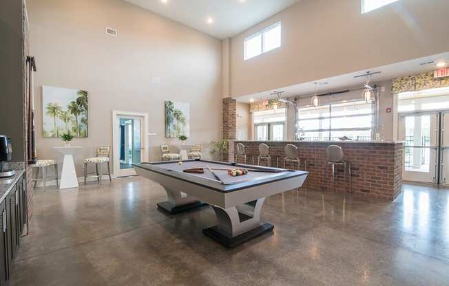 a billiards table in a clubhouse with a bar in the back