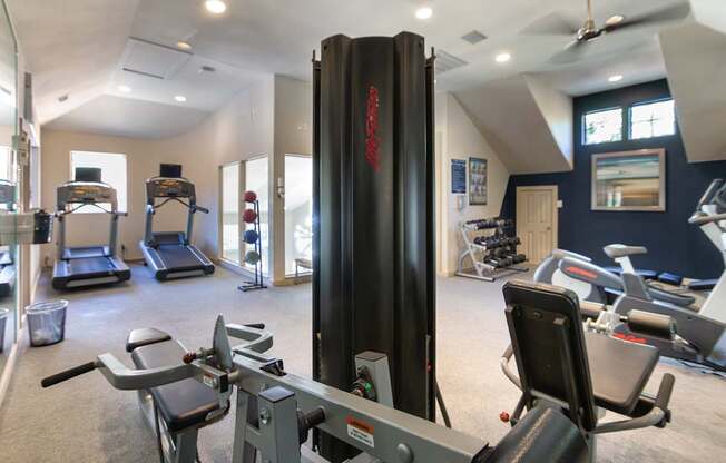 The 24-hour fitness center with treadmills, elliptical machines, and free weights at The Brownstones Townhome Apartments in the Far North Dallas neighborhood of Dallas, TX..