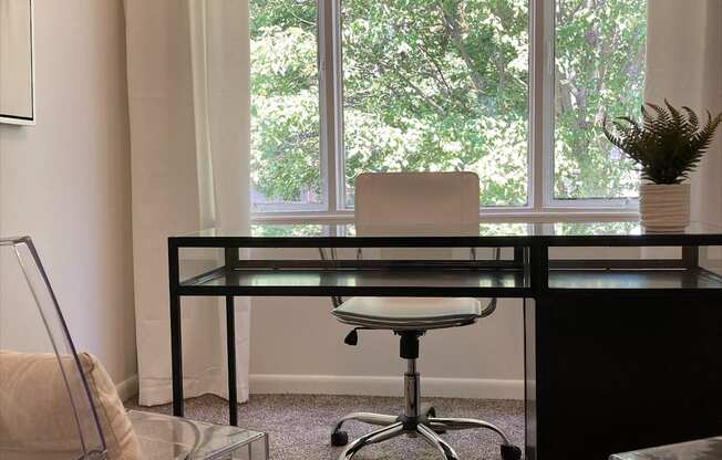 a glass desk with a chair in front of a window