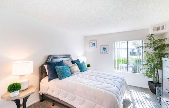 A bedroom with a large bed and a window with blinds.
