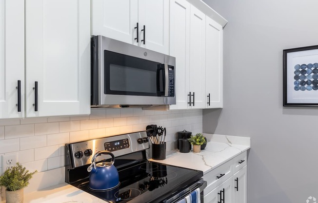 A modern kitchen with a black stove top and white cabinets.