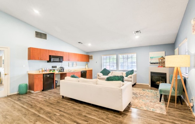 a living room with a couch a chair and a kitchen with a stove and microwave