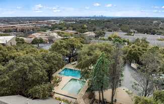 A bird's eye view of a house with a swimming pool surrounded by trees.