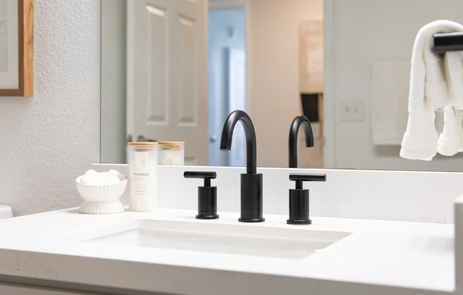 A white sink with a black faucet and a white bowl with a white substance in it.