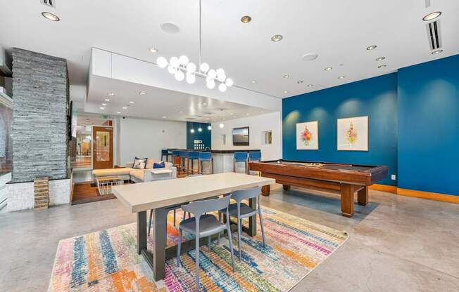 A room with a long table and chairs, a stone fireplace, and a colorful rug.