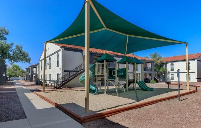 A playground with a green canopy and a slide.