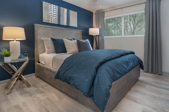 Bedroom with accent wall, hardwood-style flooring, and model furnishings at Preserve at Cedar River Apartments, Jacksonville, FL, 32210