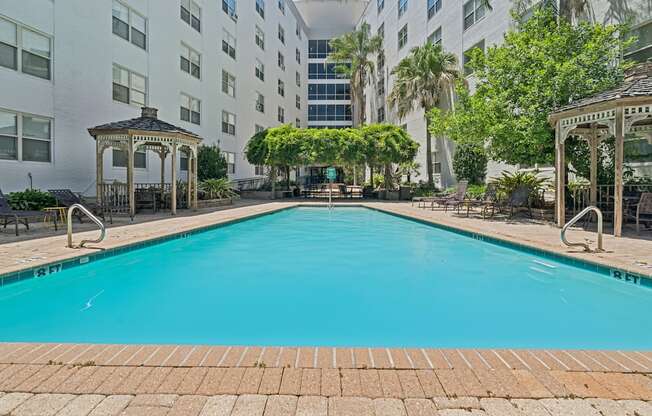 A pool surrounded by buildings and trees.