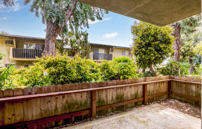 a yard with a wooden fence and a house in the background