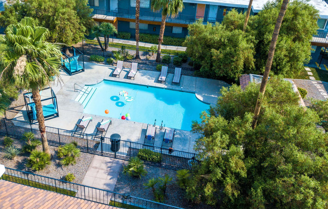 Aerial view of Fifteen 50 apartments and community pool with blue cabanas, lounge chairs, and palm tree desert landscaping.