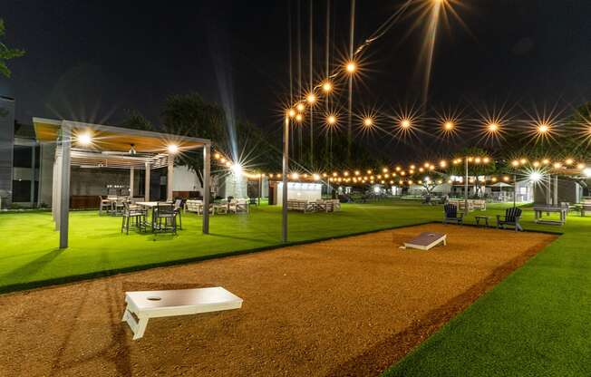 a night view of a yard with tables and chairs and lights