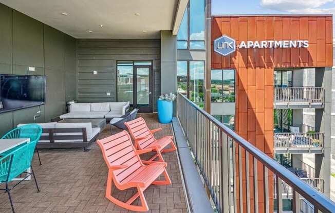 a balcony with a couch and chairs and a television at Link Apartments Innovation Quarter, Winston Salem, NC, 27101
